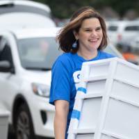 Laura Aikens carrying white storage bin for new arrival